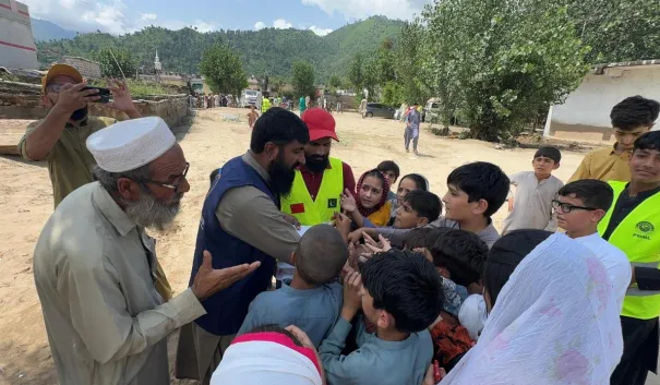 Volunteers distributing supplies to families in a Khyber Pakhtunkhwa relief camp.