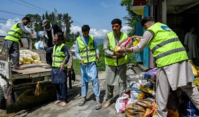 Relief workers distributing supplies in a flooded Pakistani village.