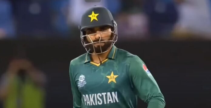Pakistani cricketer Asif Ali standing on cricket ground wearing helmet and holding bat, ready to play